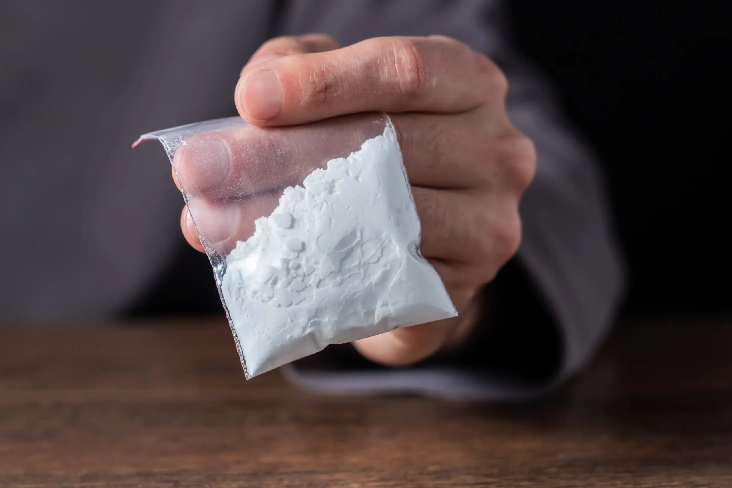 Concept drug addiction. Man hand holds plastic packet or bag with cocaine or another drugs, drug abuse and danger addiction concept