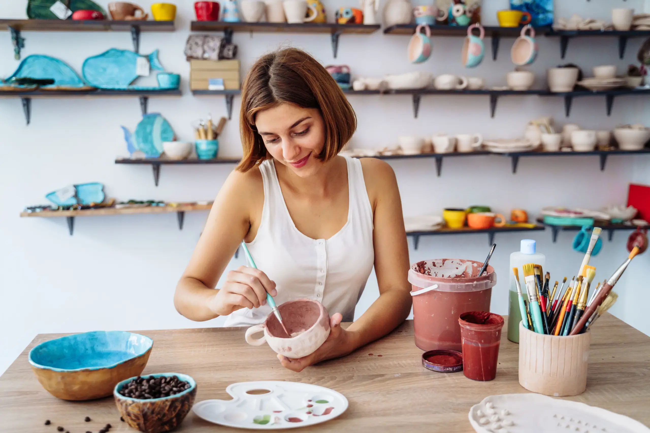 Woman in white tanktop enjpying creative procces of pottery coloring
